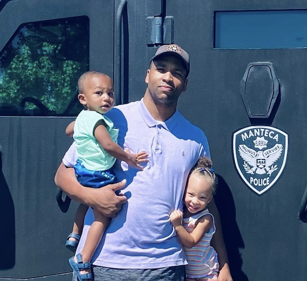 Ryan Smith holding his two kids in front of a Manteca Police vehicle